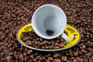 Coffee cup and plate on a pile of coffee beans