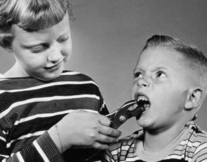 Child pulling on another child's tooth with pliers