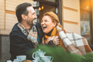 Man and woman smiling under a blanket