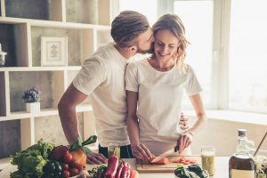 Man kissing a woman cutting a carrot