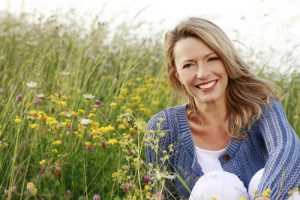 middle aged woman smiling in a field of flowers