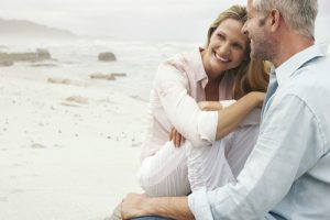 happy middle aged couple smiling at the beach