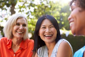 three middle-aged women laughing outdoors